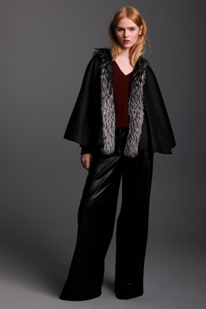 woman wearing black cashmere petite cape with silver fox trim down the front and black leather pants ful image