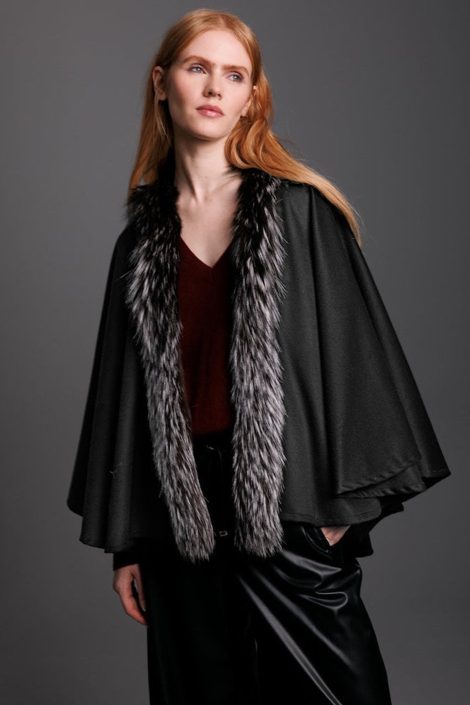 woman wearing a black petite silver fox cape with silver fox trim down the front and black leather pants