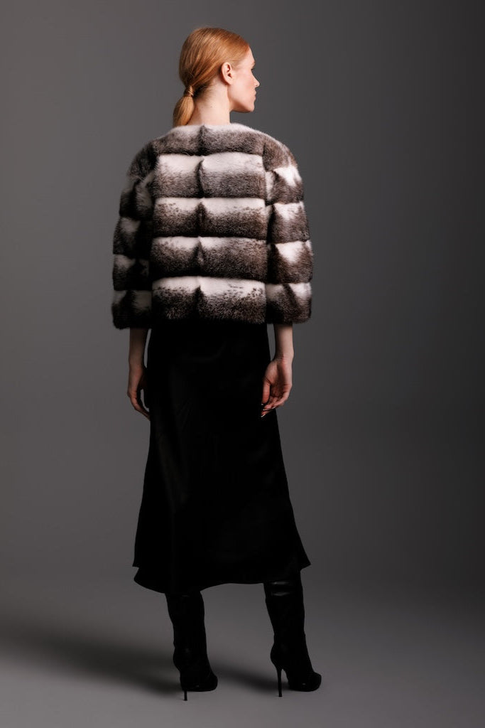 black cross mink fur jacket in horizontal pattern on woman wearing a silk dress and boots