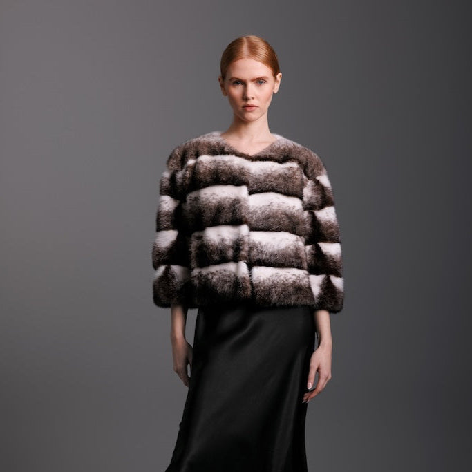 Model wearing a black cross mink jacket with black satin skirt and boots