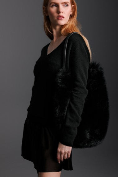 woman holding black hobo bag in shearling with short black skirt