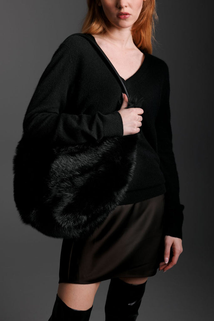 woman wearing black shearling hobo bag on shoulder and short black silk skirt and boots