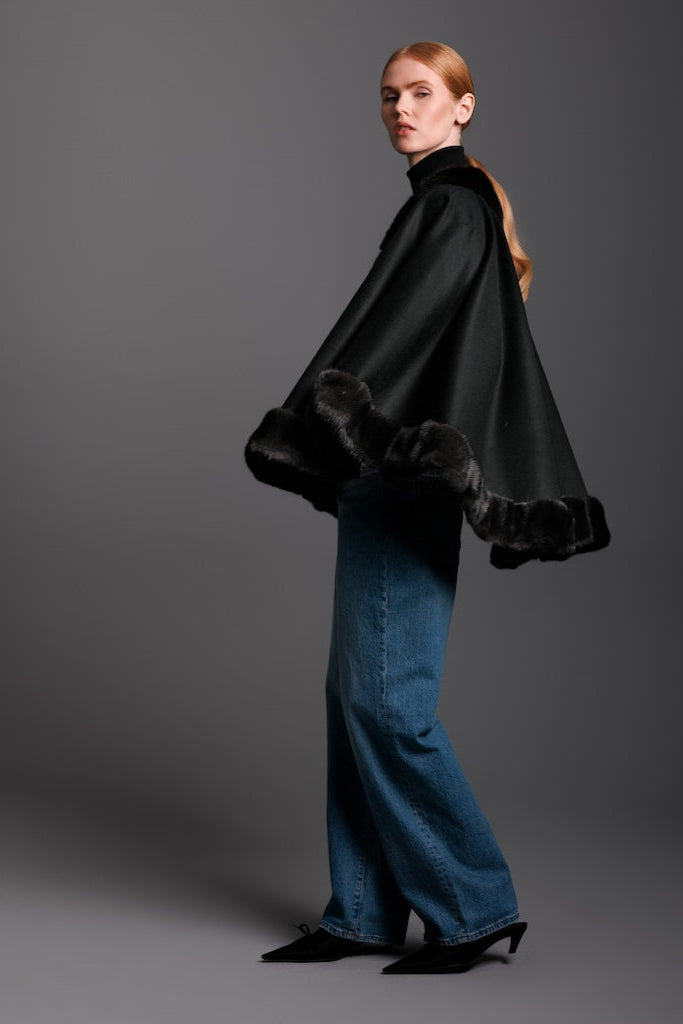 woman wearing black cashmere cape trimmed in mink and jeans and heels detail view of the side.