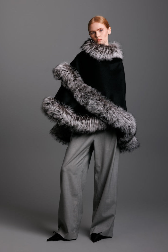 Model wearing a silver fox fur cape in petite size with black cashmere and grey pants and heels