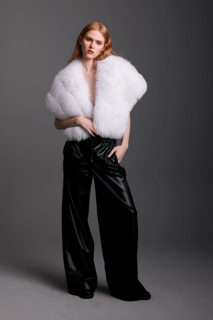 Model wearing a white fur shrug and black leather pants 