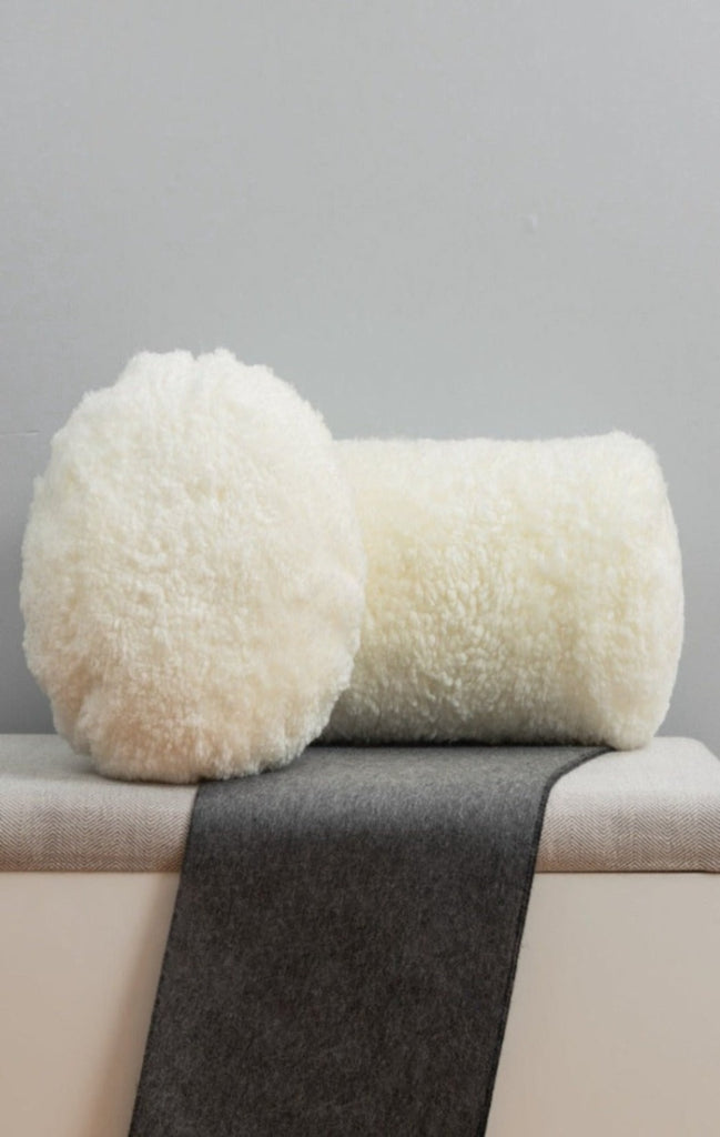 round and bolster white shearling fur pillow set on bench